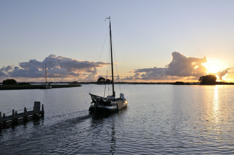 Zeilschip vaart richting ondergaande zon bij Terherne