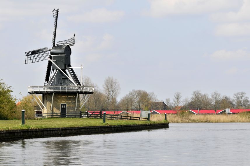 Molen bij de haven van Joure en schiphuizen op de achtergrond