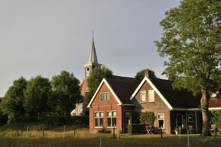 Kerk en woning in Reitsum in de avondzon