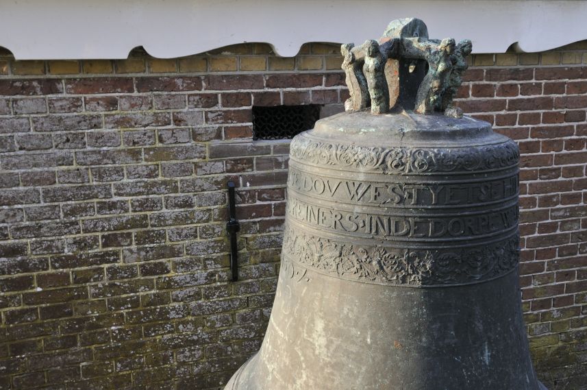 Gebarsten eeuwenoude kerkklok staat te pronk naast de kerk in Warstiens